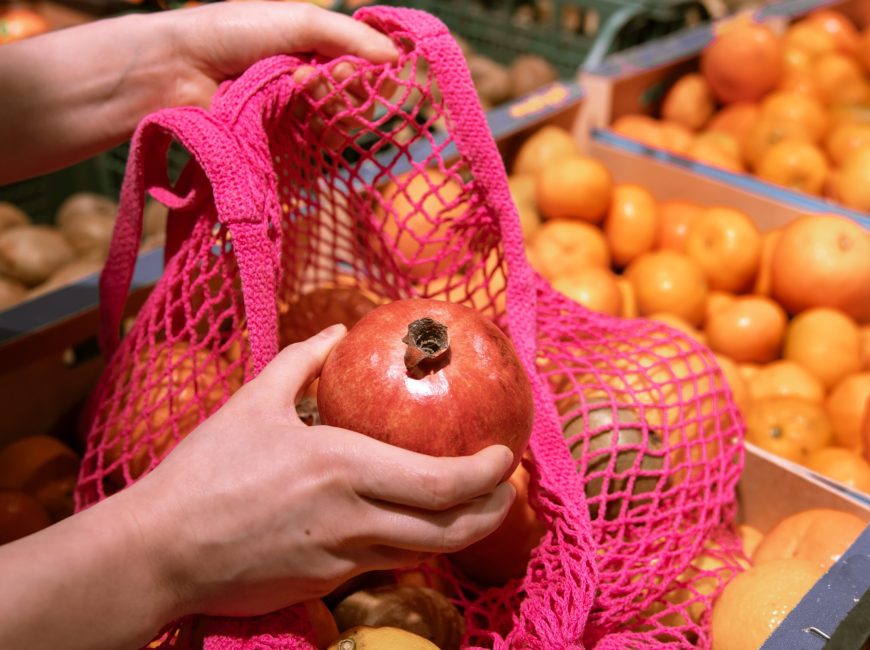 A woman in a supermarket chooses fruits and puts them in a shopping bag, the concept of healthy eating, conscious consumption, eco.